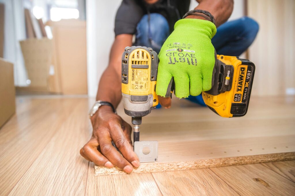 Man using a power drill for home improvement on a wooden floor with precision.
